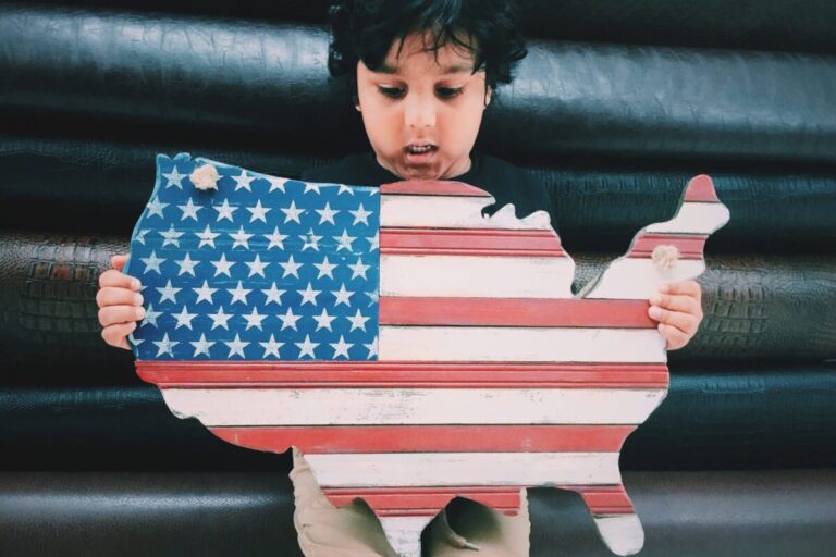How to calculate cost of living: boy holding a wooden outline of the US