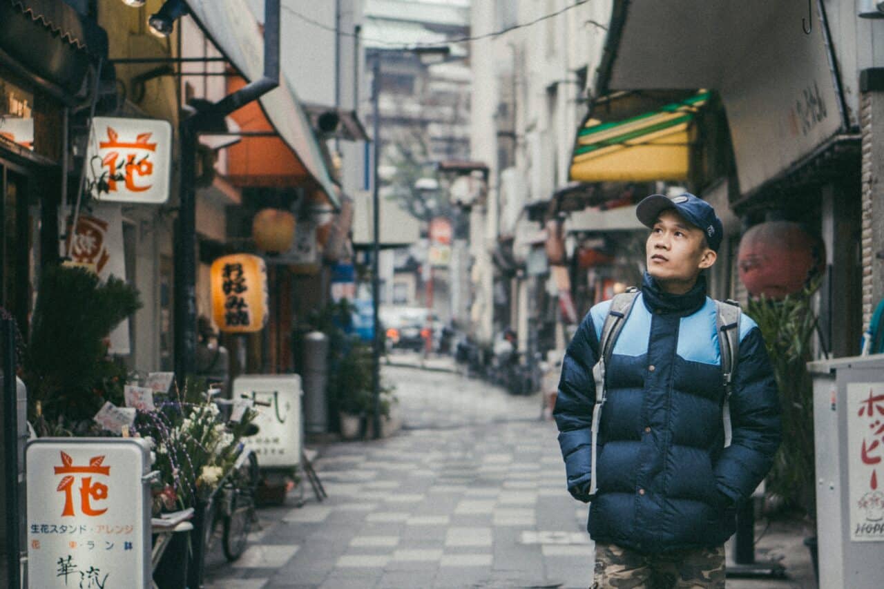 Person walking through a narrow street lined with shops in Japan.