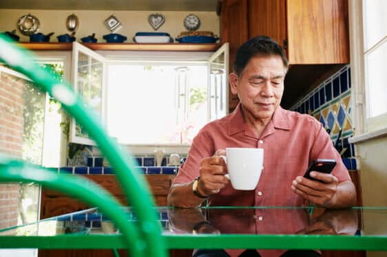 What is a SWIFT code: A man drinks coffee in his kitchen while looking at his cellphone