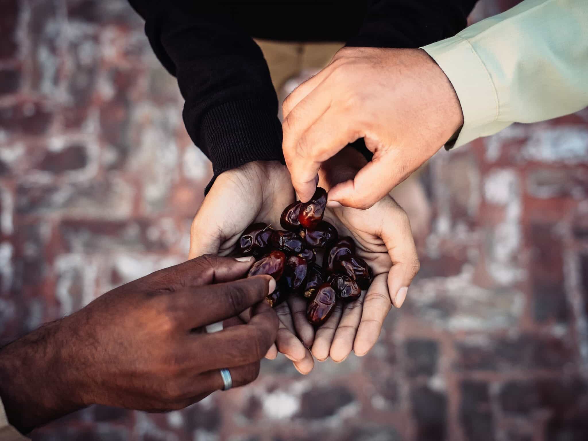 three hands choosing dates to break the Ramadan fast