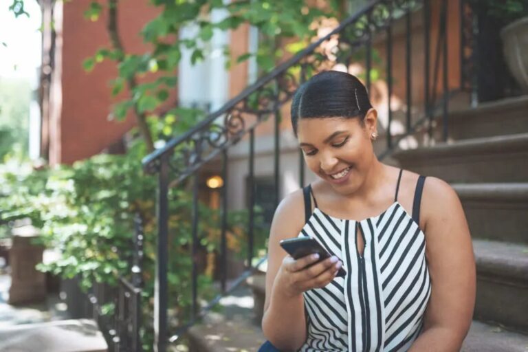 Beginner investing: woman happily using her phone