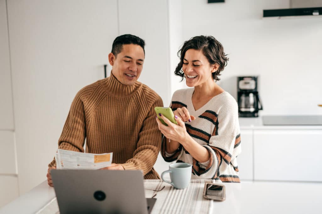 happy young couple using a budget app to manage their bills and spending