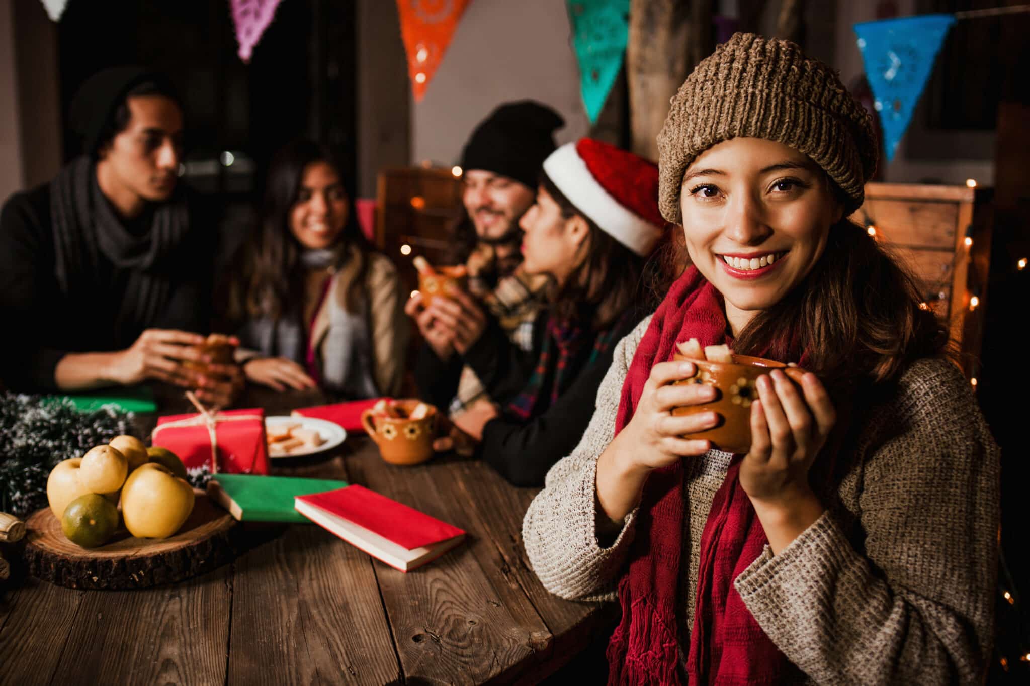 Amigos charlando alrededor de una mesa durante la época navideña