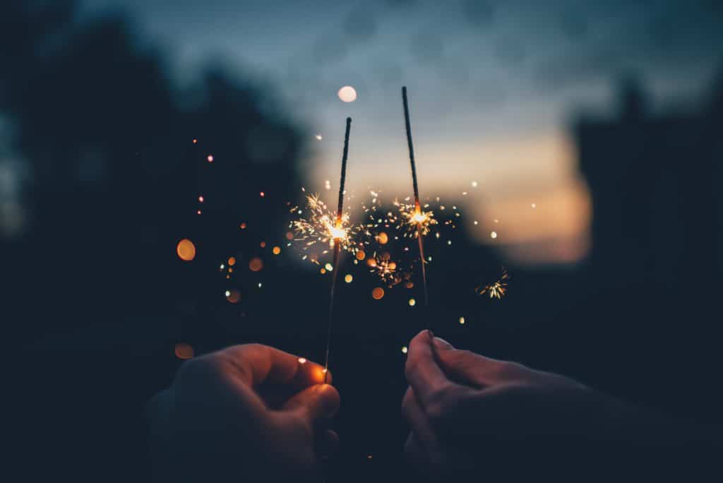 two hands holding sparklers in the dark