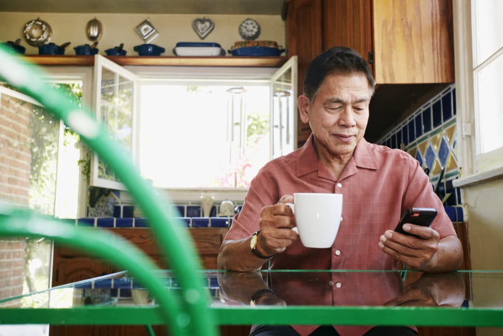 an older man is using his cell phone while sitting at a table