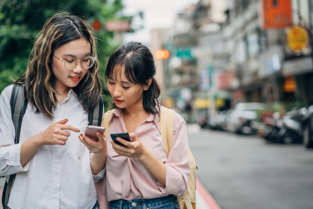 Deux jeunes femmes regardant leur téléphone portable en discutant