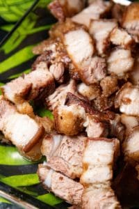 a plate of pork with a green leaf on it