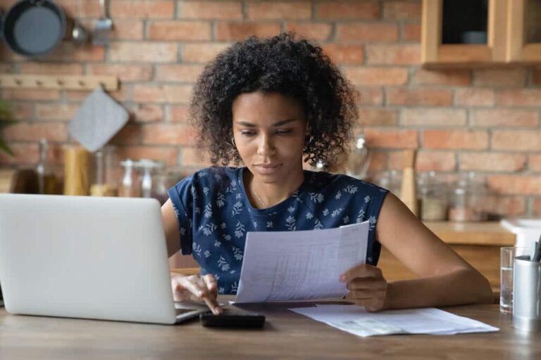 Woman using a calculator and holding a document