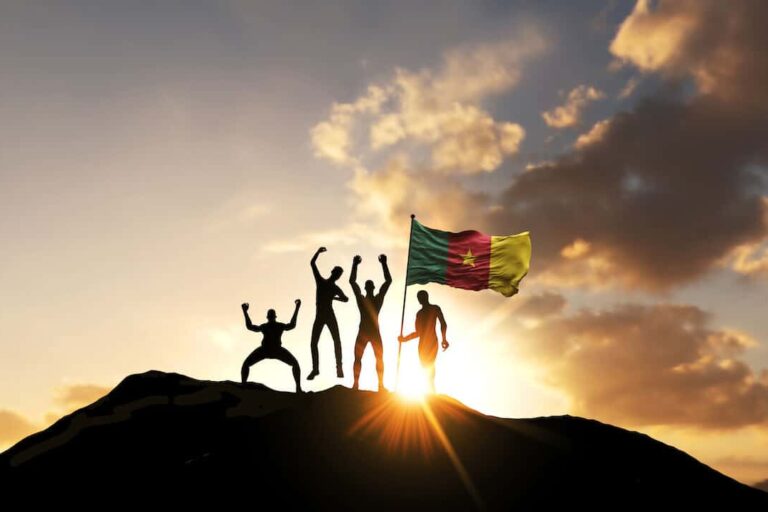 Cameroon currency: group of people with the Cameroon flag on top of a mountain