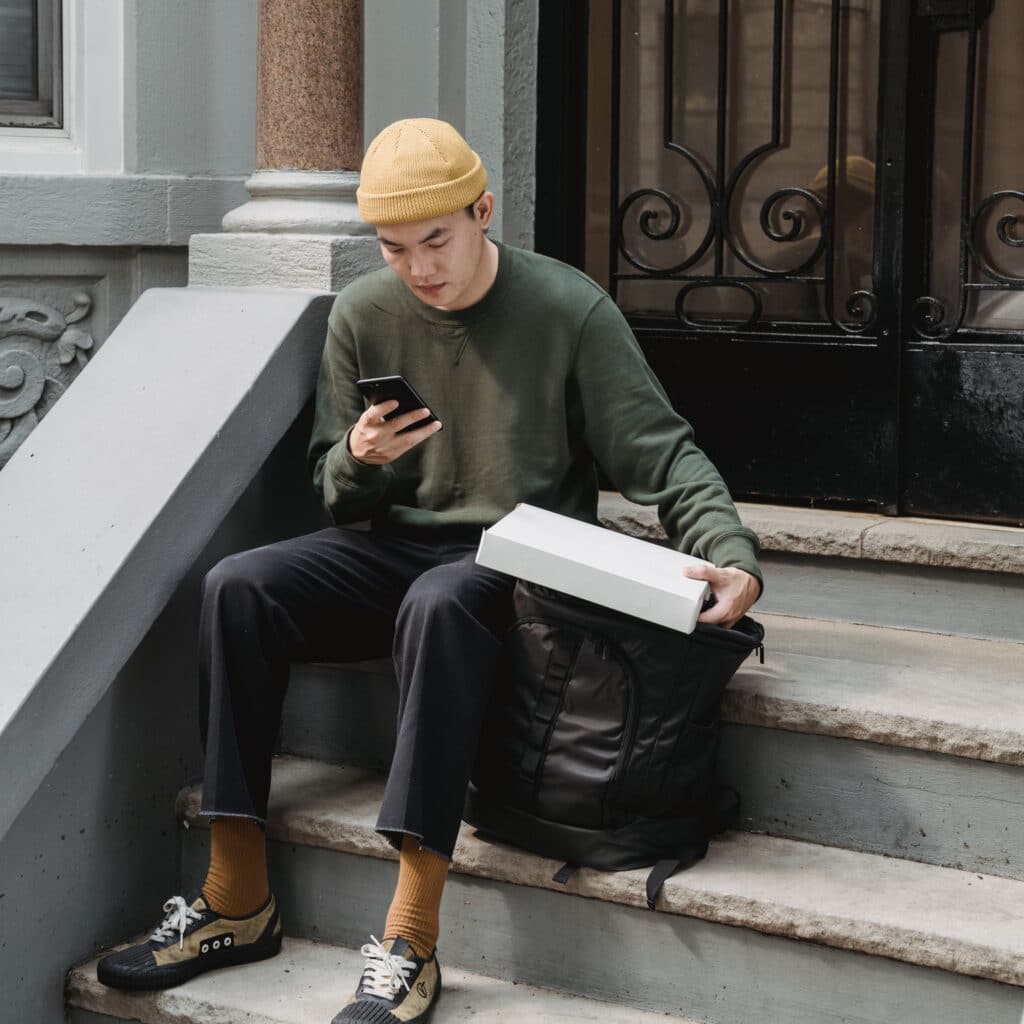 Ragazzo che usa il cellulare mentre è seduto sugli scalini di un portone