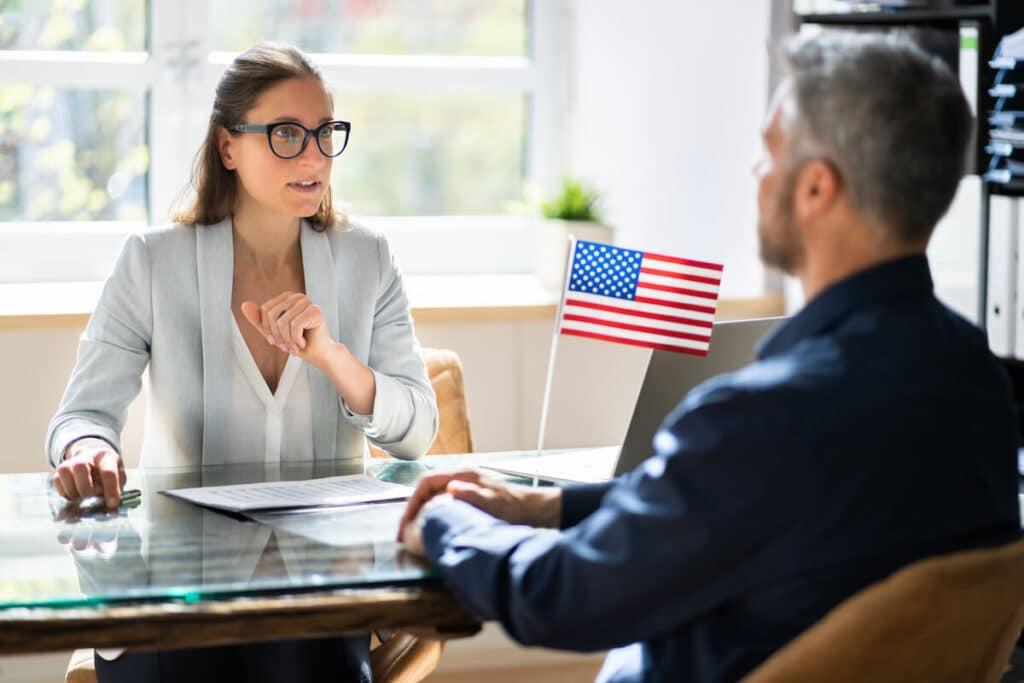 Two people have a meeting with a U.S. flag on the desk between them