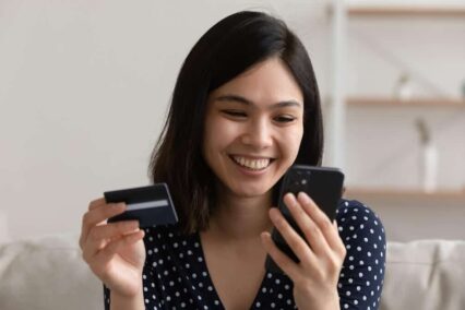 Kredi kartı tutarken telefonunu kullanan kadın