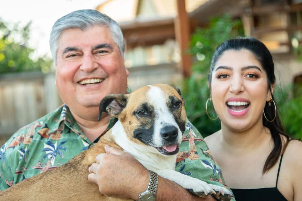 a man and woman smiling with their dog