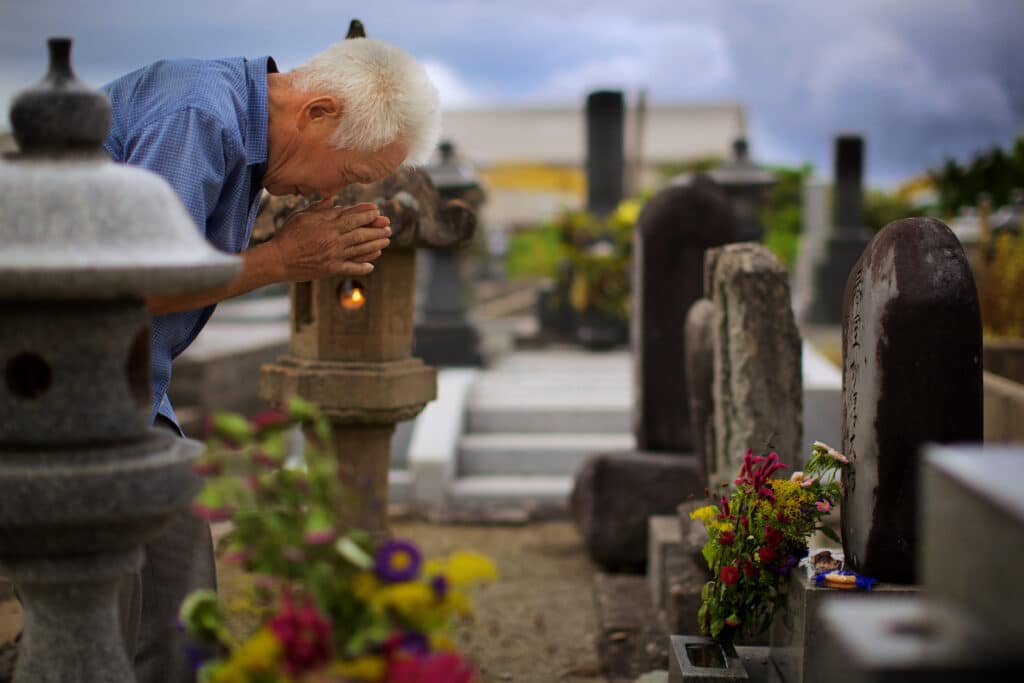 Durante el festival de Obon en Japón, un anciano presenta sus respetos a sus antepasados en el cementerio de un barrio local.