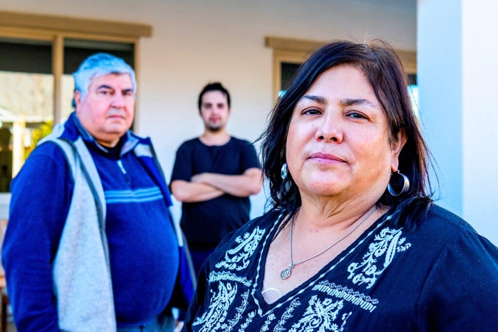 Familia hispana, madre, padre e hijo posando fuera de su patio trasero mirando a la cámara