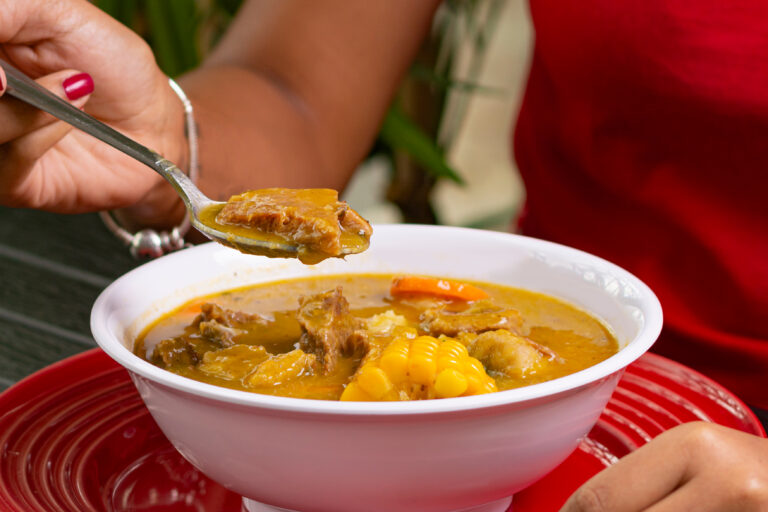 person eating sancocho soup from dominican republic