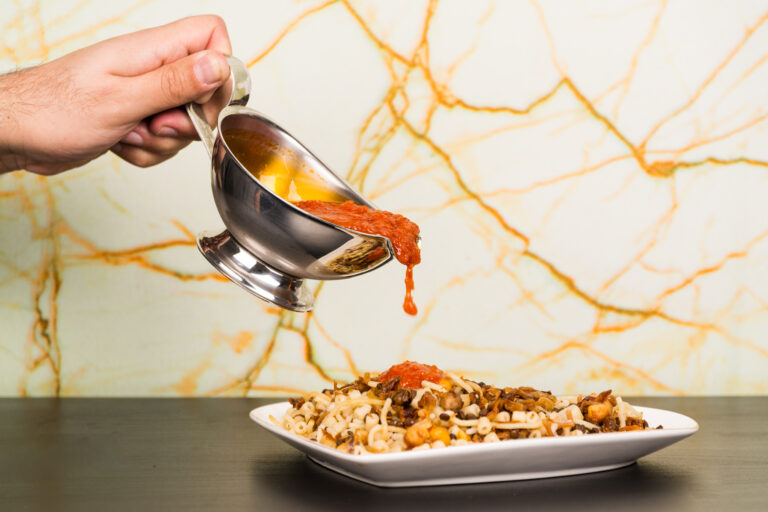 koshari with sauce being poured on it