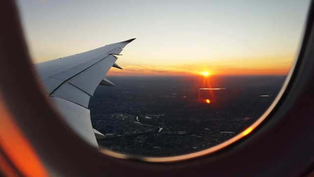 A view from a passenger's plane window, overlooking a city at sunset