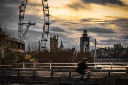 A cyclist passing in front of London landmarks like the London Eye and the Thames