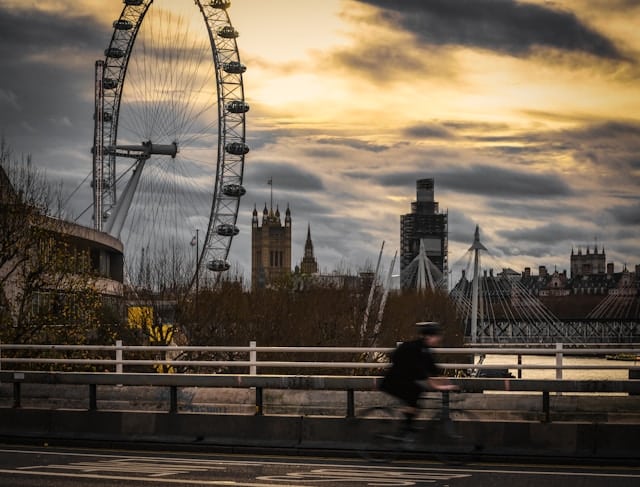 A cyclist passing in front of London landmarks like the London Eye and the Thames