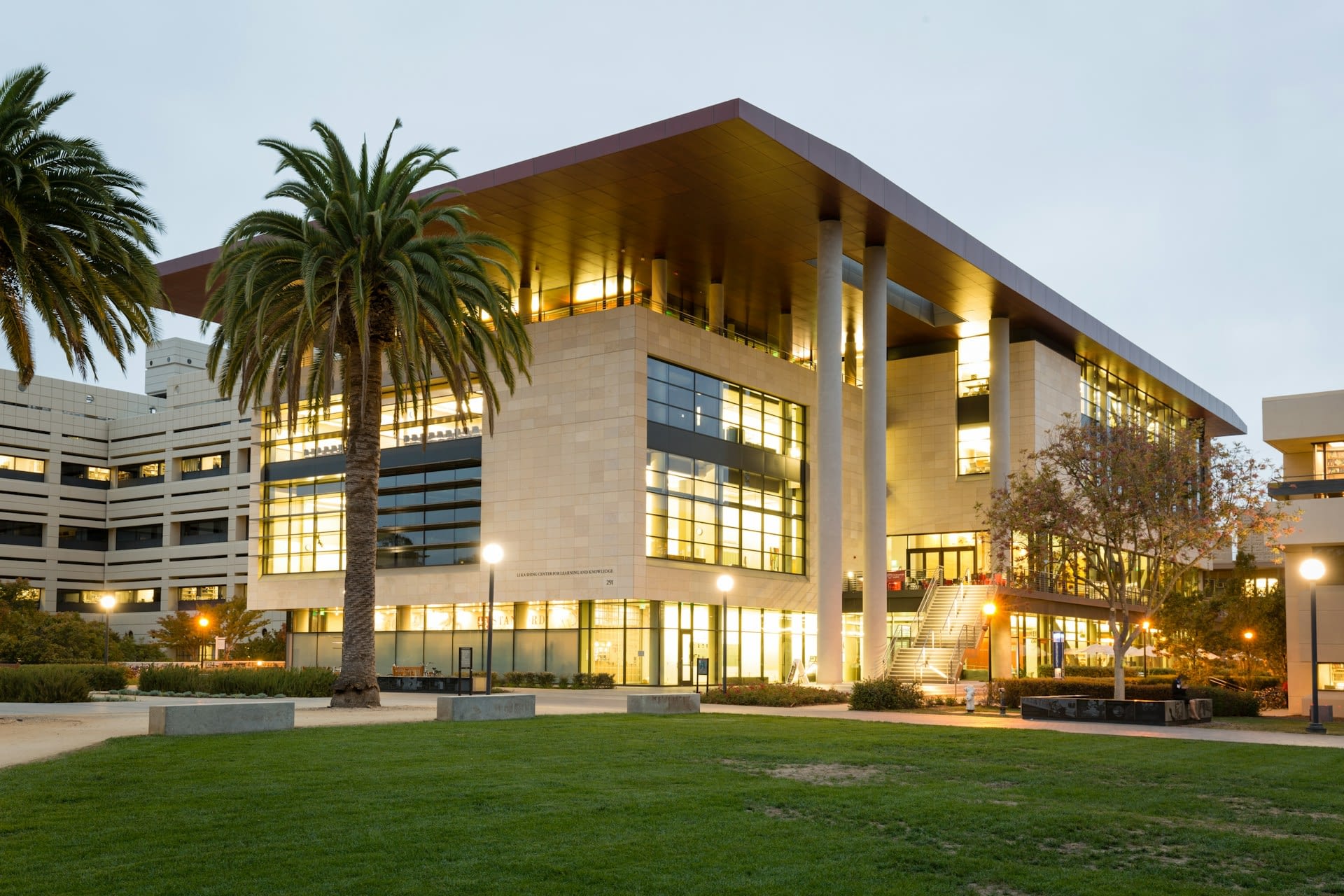 A photo of a large building near palm trees and a lawn of grass.