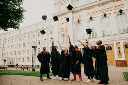 Estudiantes celebrando su graduación en un campus universitario.