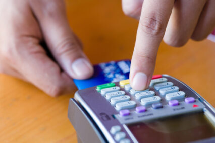 Close up customer hand holding and paying for order by credit card in cafe and restaurant.