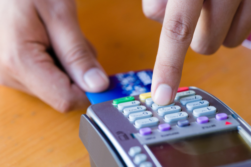 Close up customer hand holding and paying for order by credit card in cafe and restaurant.