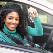 Woman holding up keys to her first new car.