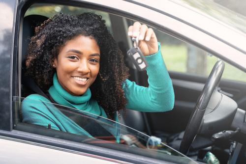 Woman holding up keys to her first new car.