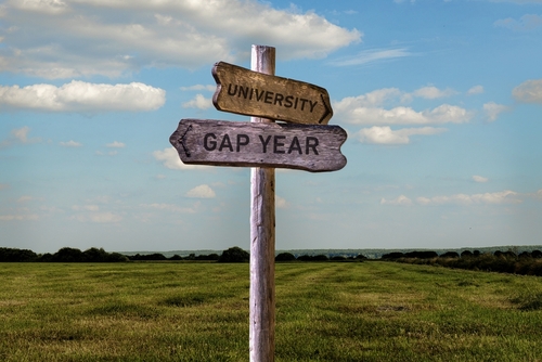 Gap year or university signpost outside. Graduation decision making process.
