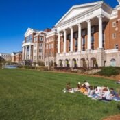 Students gather on the garden and lawn in the middle of the main buildings on the Campus of Belmont University on a sunny day with a blue sky