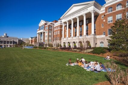 Students gather on the garden and lawn in the middle of the main buildings on the Campus of Belmont University on a sunny day with a blue sky