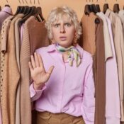 A young woman makes stop gesture asks not to spend much money on clothes.