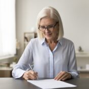 mature woman in glasses signing a document