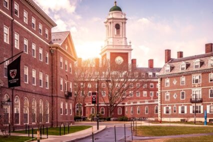 View of the architecture of the famous Harvard University in Cambridge, Massachusetts, USA showcasing it brick buildings with some students and locals passing by.