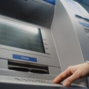 Unrecognizable person entering pin code on ATM keyboard to withdraw money.