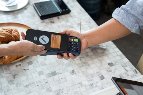Customer holding smartphone with virtual credit card screen showing