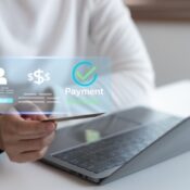 Close-up of hand holding credit card with virtual payment success interface on laptop representing secure online transaction and digital financial technology.