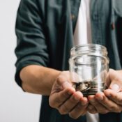 Hand of businessman holding a jar full of coins and the coins are in his palm