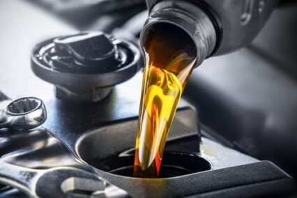 Fresh car oil being poured into a car engine.