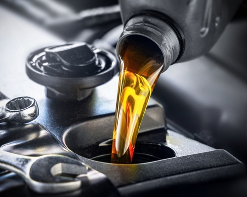 Fresh car oil being poured into a car engine.