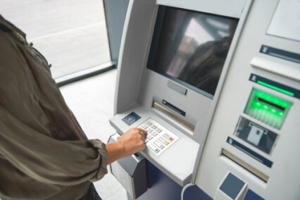 hand entering PIN number on ATM, postal code for electronic bank transfer