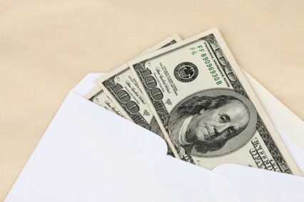 Money placed in white envelope for financial budgeting.