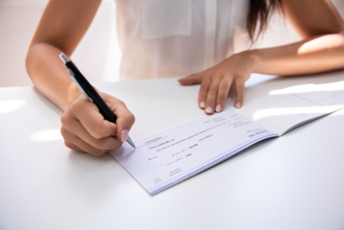 Business person signing a cheque with a pen