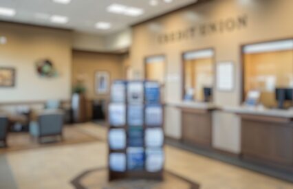 Blurred background of bright and modern credit union interior showing a welcoming atmosphere with seating, informative brochures and professional service counters for customer interactions.