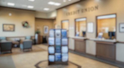 Blurred background of bright and modern credit union interior showing a welcoming atmosphere with seating, informative brochures and professional service counters for customer interactions.