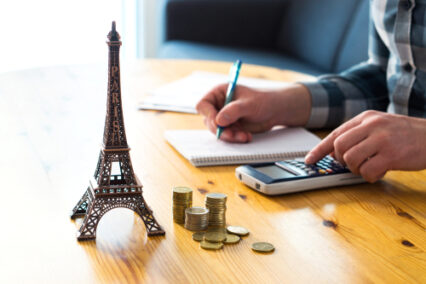Money and small Eiffel Tower souvenir from Paris on table.