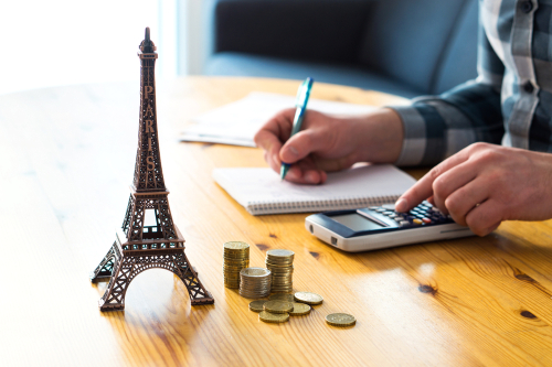 Money and small Eiffel Tower souvenir from Paris on table.