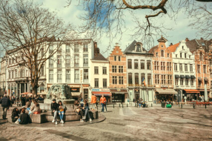 Street with many people relaxing outdoor, at square with cafe and old buildings of historical city in Brussels